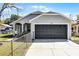 Charming single-story home with a gray exterior, dark garage door, and a well-maintained front yard at 1613 N Lakewood Ave, Ocoee, FL 34761