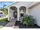 Inviting covered porch features neutral brick pavers, seating area, and decorative black front door at 1613 N Lakewood Ave, Ocoee, FL 34761