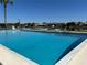 Community pool with clear blue water and surrounding lounge chairs overlooking a lake at 1920 E Edgewood Dr # A5, Lakeland, FL 33803