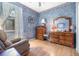 Bedroom featuring a large dresser, chair, and wood flooring under blue textured walls at 2029 Majestic Elm Blvd, Ocoee, FL 34761