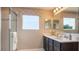 Well-lit bathroom featuring double sinks, shower, dark cabinets, and a large window at 2743 San Marco Way, Winter Haven, FL 33884