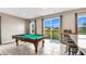 The billiard room is flooded with natural light from the large windows showcasing the pool table at 3005 Slough Creek Dr, Kissimmee, FL 34744