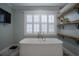 Modern bathroom with a luxurious soaking tub, shuttered windows, and floating wooden shelves at 31707 Orange St, Sorrento, FL 32776