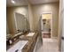 Bathroom with double sinks, granite countertop, large mirror, and a walk in closet at 3191 Brasilia Ave, Kissimmee, FL 34747