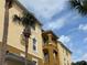 Low angle building exterior showing balconies on a yellow stucco building with palm trees against a blue sky at 4814 Cayview Ave # 407, Orlando, FL 32819