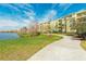 Building exterior along a lake with a walking trail surrounded by green grass and trees under a blue sky at 4814 Cayview Ave # 407, Orlando, FL 32819