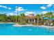 A community pool featuring a nearby covered bar, surrounded by palm trees, lounge chairs, and dining sets at 4814 Cayview Ave # 407, Orlando, FL 32819