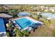 Aerial view of a large community pool with chairs, palm trees, tennis courts and tropical landscaping at 5025 St Andrews Arc, Leesburg, FL 34748