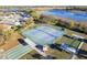 Aerial view of tennis courts with bocce ball, shuffleboard courts, and lush green surroundings near a lake at 5025 St Andrews Arc, Leesburg, FL 34748