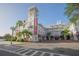 Exterior shot of a charming multi-story white hotel with a distinctive tower, palm trees and striped awnings at 506 Mirasol Cir # 202, Celebration, FL 34747