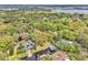 Aerial view featuring a home nestled among lush trees and a large lake in the distance at 5374 Crooked Oak Cir, St Cloud, FL 34771