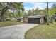 View of house with two-car garage, concrete driveway, and landscaped yard with mature trees at 5374 Crooked Oak Cir, St Cloud, FL 34771