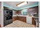 Galley kitchen featuring a black refrigerator, dark cabinets, and a large window above the sink at 6424 Jenny Dr, Lake Wales, FL 33898