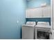 Bright laundry room featuring a modern washer and dryer set, complemented by white cabinets against a blue accent wall at 6854 Remington View Ct, Orlando, FL 32829