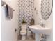 Stylish powder room featuring floral wallpaper, a pedestal sink, and modern fixtures at 7407 Ripplepointe Way, Windermere, FL 34786