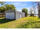 Garage with a large roll-up door and side service door, set on a grassy lot near a lake at 9744 Cub Cv, Apopka, FL 32703