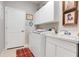 Well-lit laundry room includes a washing machine, cabinets, sink, and access door at 10544 Spring Lake Dr, Clermont, FL 34711