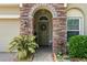 Charming front entrance with stone archway, a decorative wreath, and lush landscaping at 10942 High Bush Ct, Orlando, FL 32825