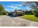 Exterior view of home with a long driveway, mature trees, and a green lawn at 17220 Countrybrook Ln, Orlando, FL 32820