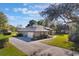 Aerial view of home with driveway, mature trees, and lush green lawn at 17220 Countrybrook Ln, Orlando, FL 32820