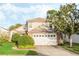 Exterior of a two-story home with a two car garage, lush landscaping, and a well maintained front lawn at 1751 Meadowgold Ln, Winter Park, FL 32792