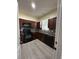 Efficient kitchen featuring dark wood cabinetry, black appliances, and modern backsplash at 178 Chippendale Ter, Oviedo, FL 32765