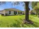 Expansive backyard with green grass, mature trees, and a view of the home's exterior and landscaping at 24515 Bocage Way, Leesburg, FL 34748