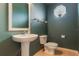 A stylish powder room featuring a pedestal sink, toilet, and a decorative mirror at 24515 Bocage Way, Leesburg, FL 34748
