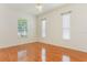 Bright bedroom featuring hardwood floors, a ceiling fan, and windows overlooking the front yard at 24515 Bocage Way, Leesburg, FL 34748
