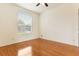 This cozy bedroom features hardwood floors, a ceiling fan, and a large window providing natural light at 24515 Bocage Way, Leesburg, FL 34748