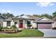 Charming single-story home boasts a well-manicured lawn and a bright red front door at 24515 Bocage Way, Leesburg, FL 34748