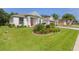 Well-maintained home with lush green lawn and colorful landscaping surrounding the front entrance at 24515 Bocage Way, Leesburg, FL 34748
