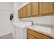 Functional laundry room with wooden cabinets, washer, dryer, and utility sink for added convenience at 24515 Bocage Way, Leesburg, FL 34748