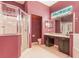 This bathroom features a walk-in shower, tiled floors, and a dual sink vanity with a large mirror at 24515 Bocage Way, Leesburg, FL 34748