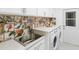 Functional laundry area with vibrant backsplash, sink, and modern appliances at 30912 Fairvista Dr, Tavares, FL 32778