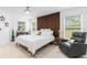 Serene main bedroom with a wood accent wall, cozy furniture, and bright windows creating a relaxing retreat at 30912 Fairvista Dr, Tavares, FL 32778