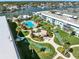 Aerial view showcasing community amenities like the pool, shuffleboard, fire pit and tropical landscaping along the waterfront at 325 N Causeway # 2080, New Smyrna Beach, FL 32169