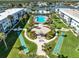 Aerial view showcasing a community with a pool, shuffleboard courts, and fire pit amidst lush landscaping and waterfront access at 325 N Causeway # 2080, New Smyrna Beach, FL 32169