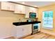 This is a kitchen featuring white cabinets, black counters, and stainless steel appliances at 5108 Sunrise Blvd, Orlando, FL 32803