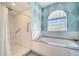 Elegant bathroom featuring a soaking tub, tiled shower, and a stylish window for natural light and ventilation at 5170 Ne 64Th Ave, Silver Springs, FL 34488