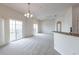 Bright living room featuring carpet, two sliding glass doors to balcony, ceiling fan and kitchen view at 6612 S Goldenrod Rd # 104A, Orlando, FL 32822