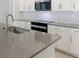 Close-up shot showcasing a kitchen island with gray countertop, a stainless steel sink, and white cabinetry at 8007 Colby Cir, Orlando, FL 32817