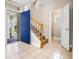 Bright foyer featuring tile floors, a wooden staircase, and a vibrant blue front door at 8426 Foxworth Cir # 44, Orlando, FL 32819