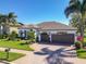 Stunning single-story home featuring a three-car garage, a brick driveway, and lush tropical landscaping at 9661 Portofino Dr, Orlando, FL 32832