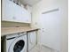 Functional laundry room featuring white cabinets, washer, dryer, and a tiled floor at 9661 Portofino Dr, Orlando, FL 32832