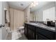 Bathroom with modern fixtures, dark vanity, granite countertop, and shower-tub combo, offering functionality at 10849 Wyne Tree Ct, Orlando, FL 32824