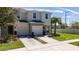 Two-story tan townhome featuring an attached garage, lush lawn, and a vibrant palm tree at 10849 Wyne Tree Ct, Orlando, FL 32824