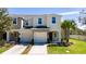 Two-story tan townhome featuring an attached garage, lush lawn, and a vibrant palm tree at 10849 Wyne Tree Ct, Orlando, FL 32824