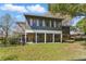 Home's back exterior view featuring an elevated deck, patio, fenced yard, and lush landscaping at 13224 Casper Ln, Clermont, FL 34711