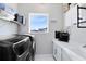 Laundry room features black front-load machines, shelving, and white cabinetry at 13800 Chauvin Ave, Orlando, FL 32827